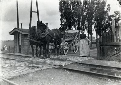 172180 Afbeelding van een paard en wagen met twee personen in Zeeuwse klederdracht bij een spoorwegovergang bij Goes.